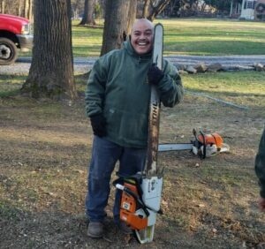 A man standing beside a giant chain saw